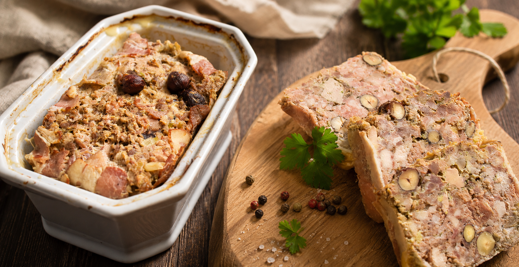 Terrine de viande aux herbes et noisettes, tranchée sur planche en bois, avec plat au premier plan.