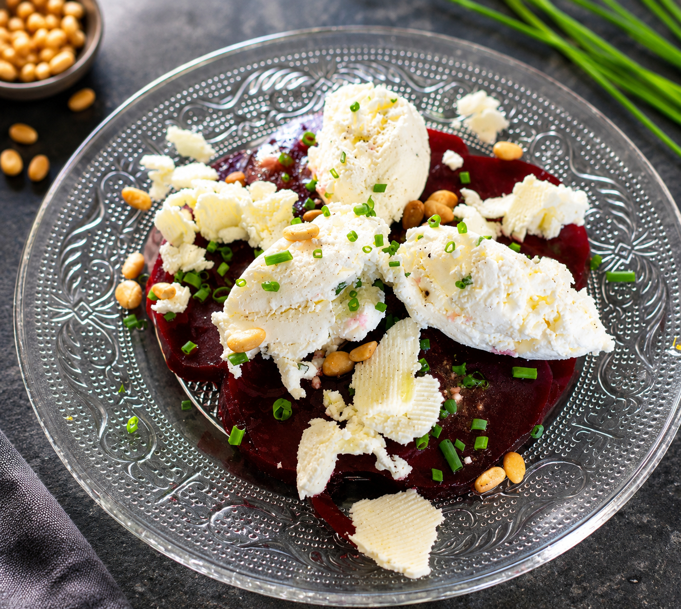Assiette avec carpaccio de betteraves et quenelles de fromage de chevre avec ciboulette verte et pignons grillés.