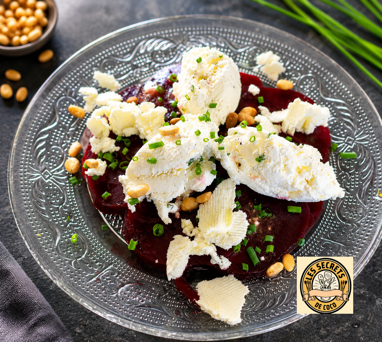 Assiette avec carpaccio de betteraves et quenelles de fromage de chevre avec ciboulette verte et pignons grillés.