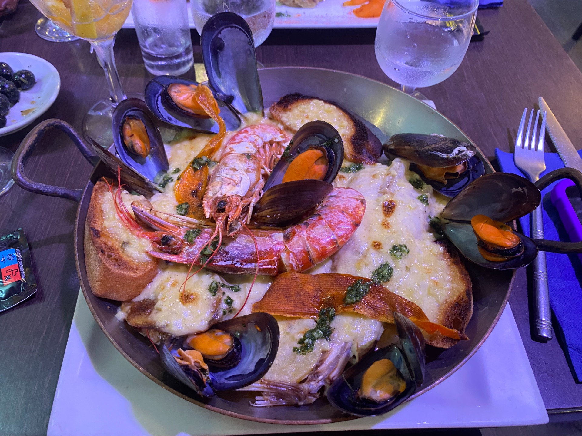 Assiette de fruits de mer avec moules, crevettes et pain, nappée de sauce blanche, sur table. Bourride