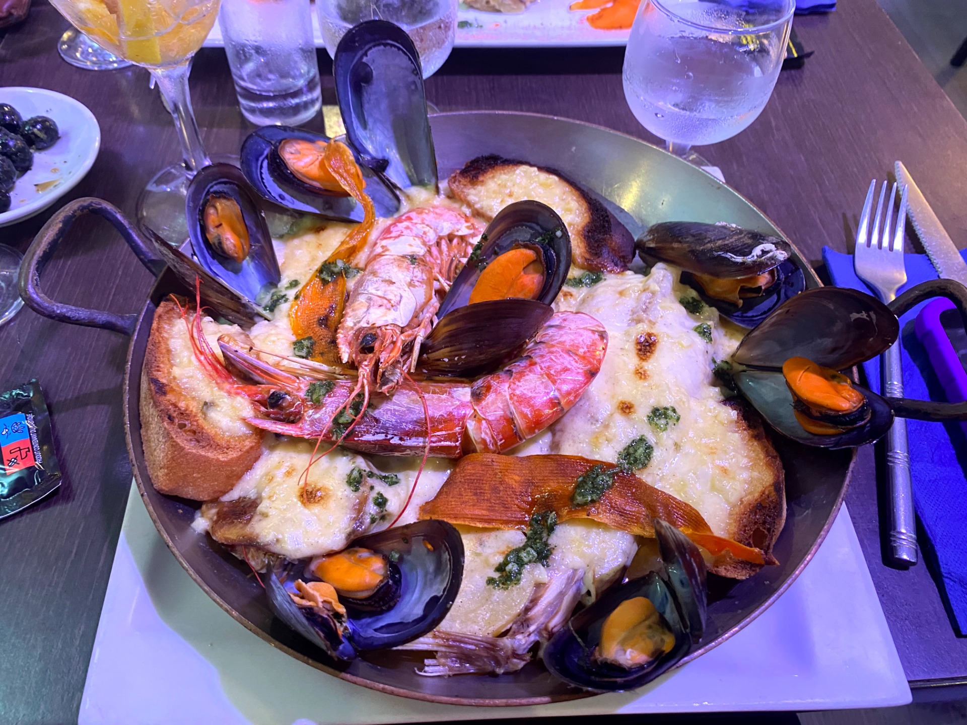 Assiette de fruits de mer avec moules, crevettes et pain, nappée de sauce blanche, sur table. bourride