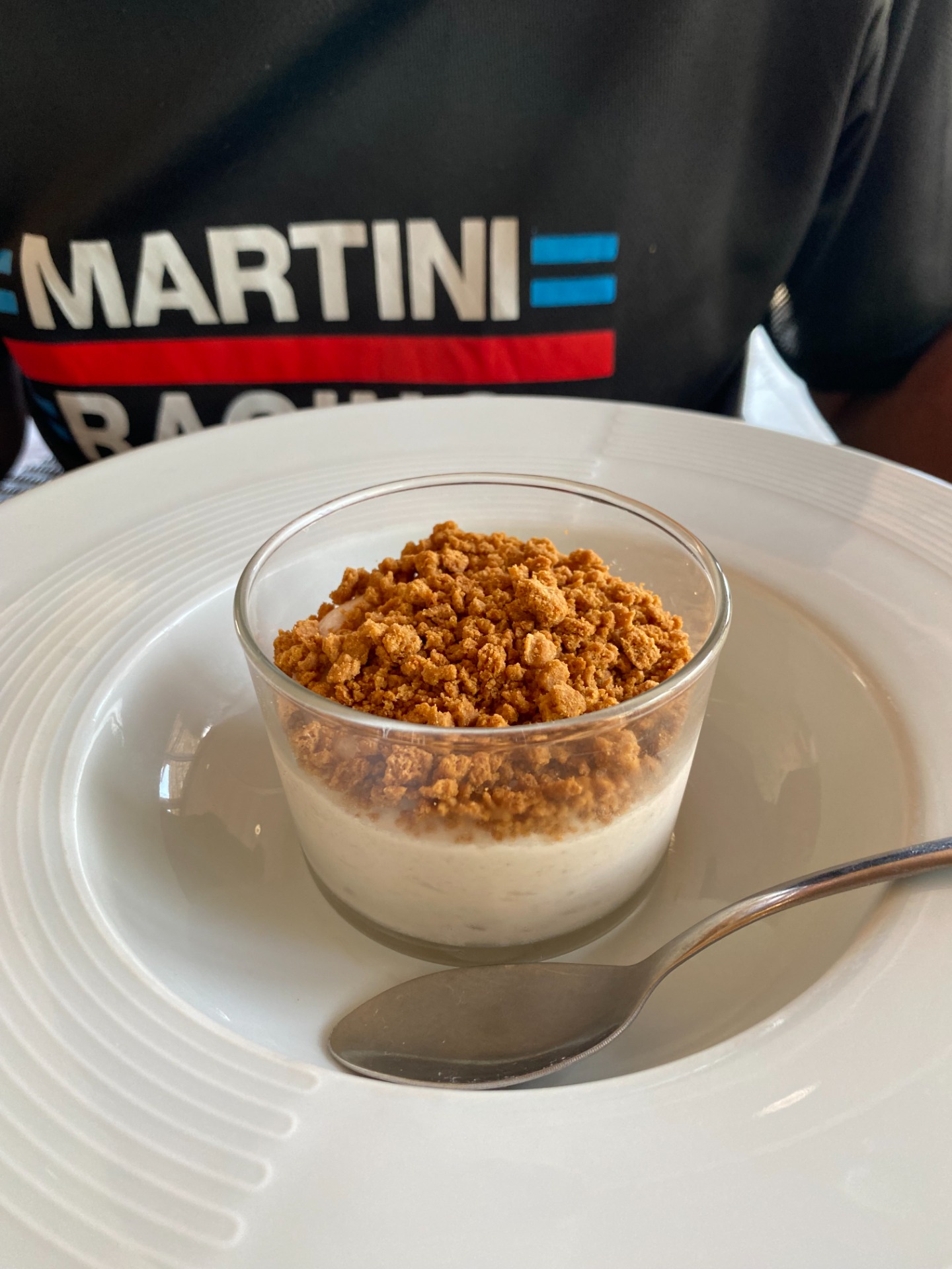 Verrine de marron suisse urmontée de miettes croustillantes, servie sur assiette blanche, logo “MARTINI” en arrière-plan.