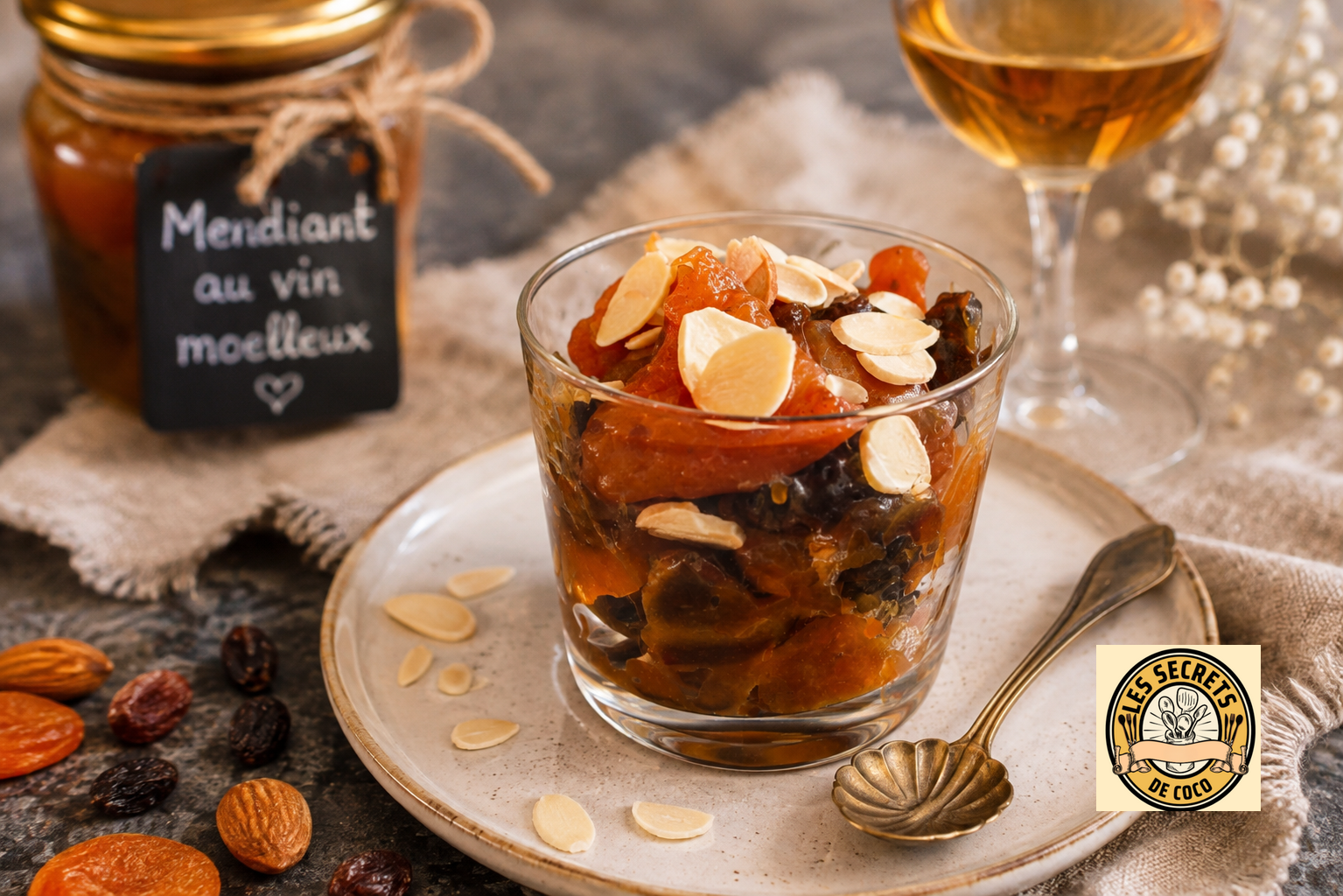 Verre couler ambrée aux fruits secs, amandes effilées, sur plateau beige, avec étiquette “Mendiant au vin moelleux”.