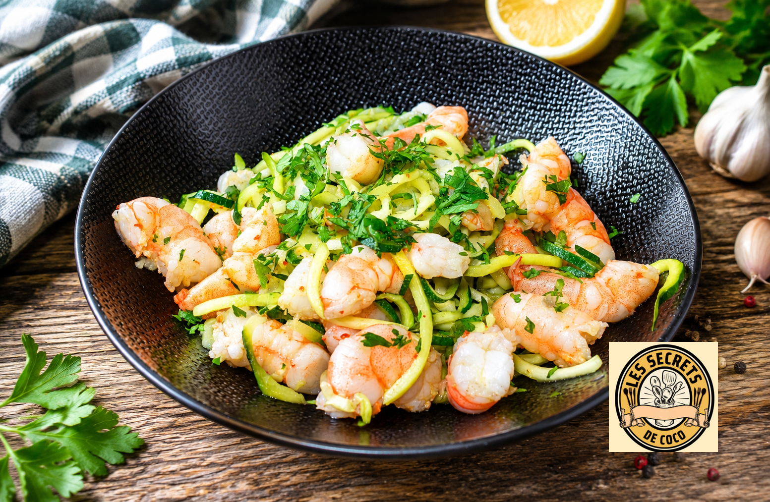 assiette de crevettes et courgettes spiralées, herbes fraîches, citron, ail et poivre, dans un bol noir.