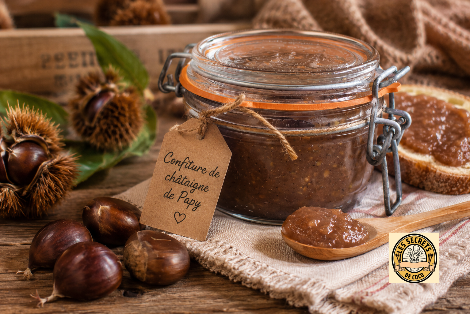 Bocal en verre de confiture de châtaigne, étiquette artisanale, châtaignes et pain sur table rustique.