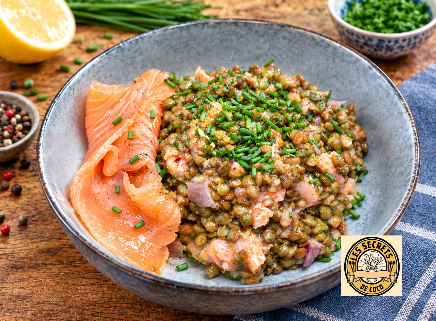 Bol de lentilles aux herbes, saumon fumé et citron, sur table rustique, avec bols d’épices en arrière-plan.